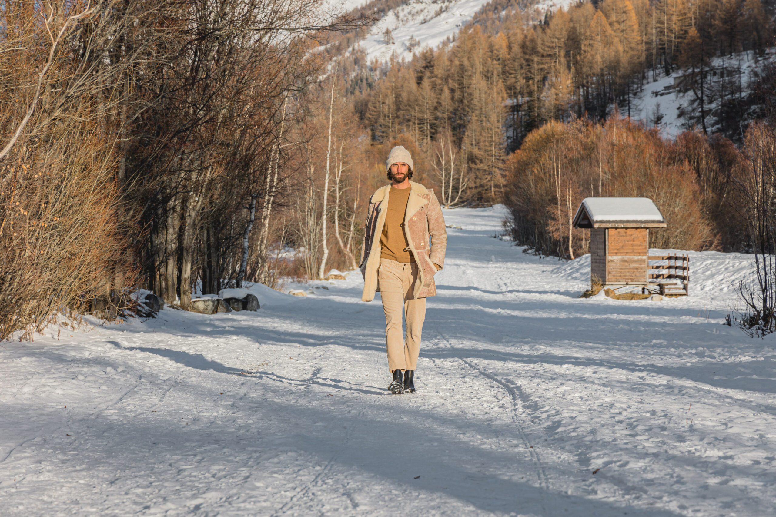 Modello indossa maglione a collo alto e stivaletti mentre cammina in montagna
